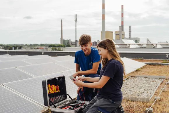 Zwei Techniker prüfen eine Photovoltaikanlage auf einem Flachdach